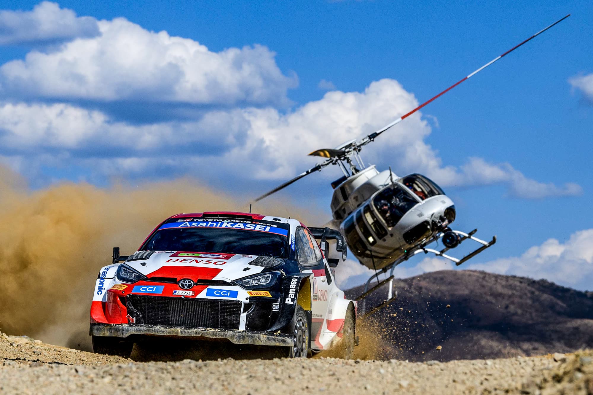 Broadcast helicopter flying close aerial coverage of a WRC rally car in Mexico