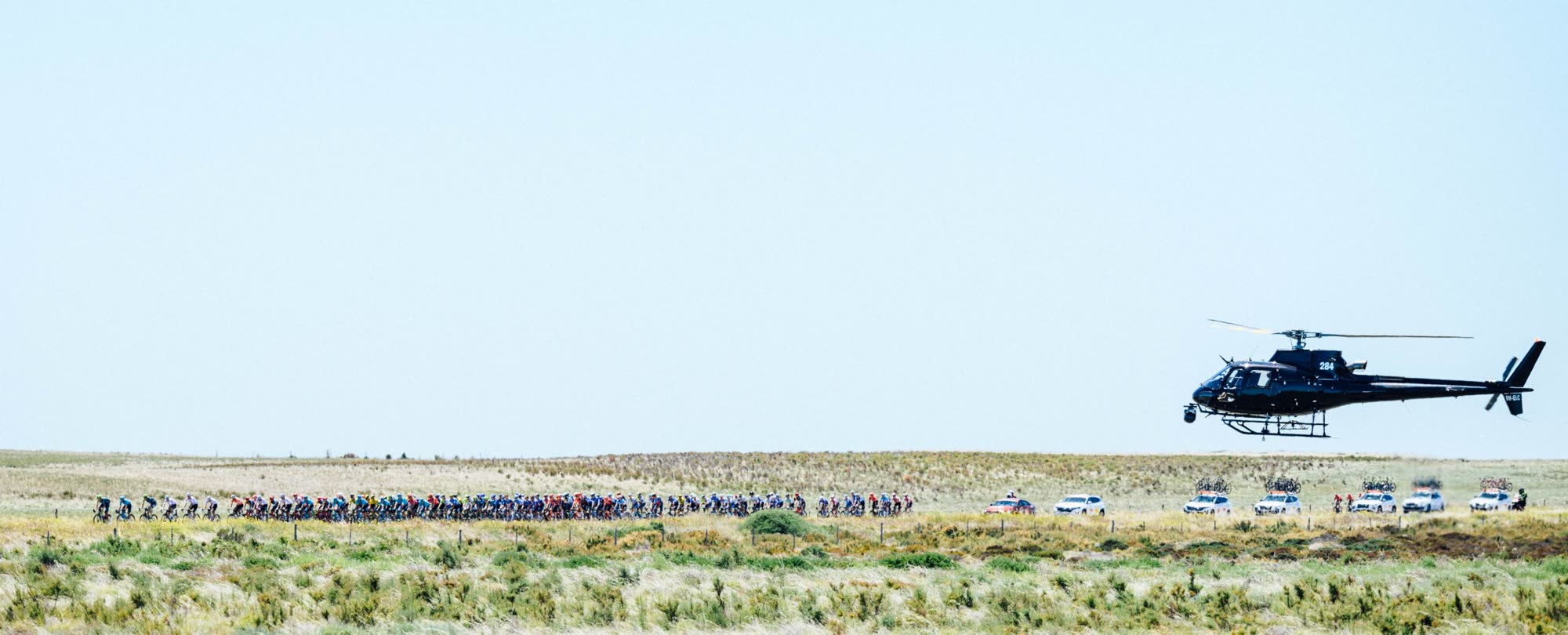 Wide aerial broadcast shot of the Tour Down Under cycling peloton from a helicopter