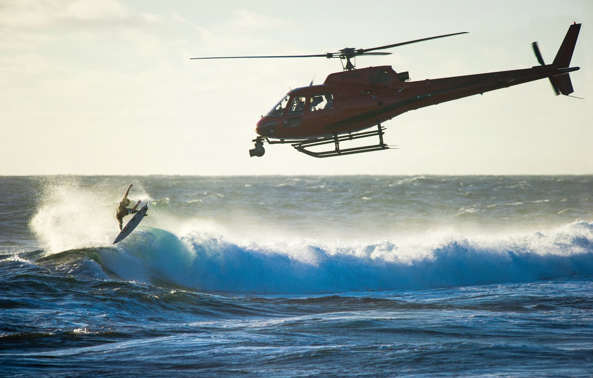 Helicopter aerial filming of professional surfing from low over the ocean