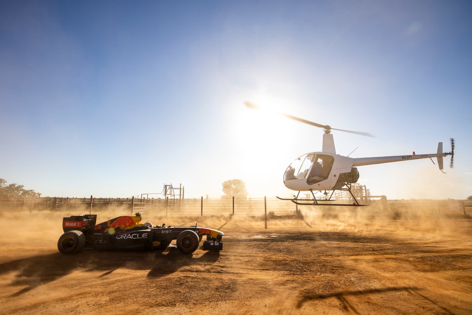 Helicopter stunt flying in formation with a Formula 1 car for a Red Bull shoot