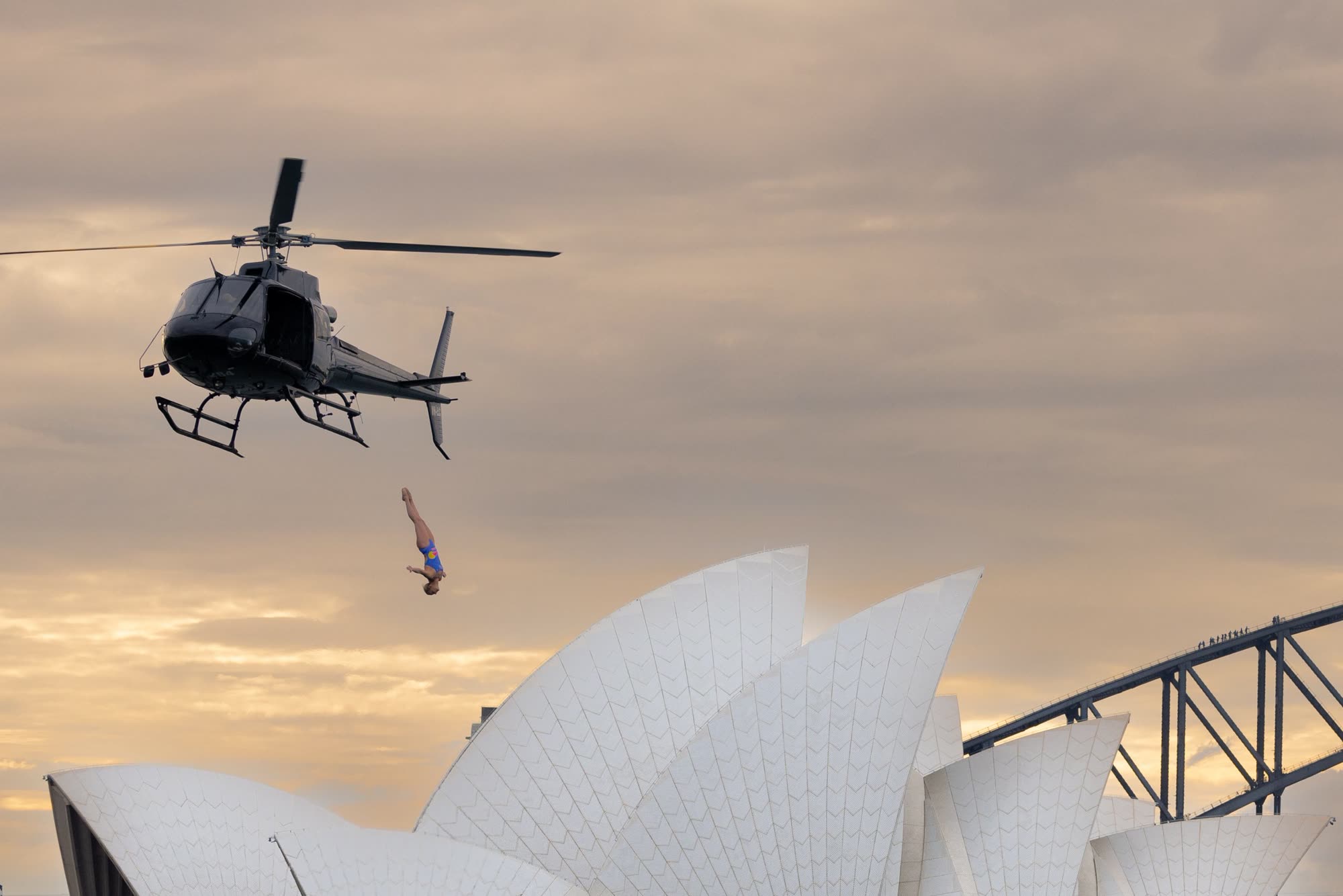 Stunt performer diving from a helicopter skid during a coordinated aerial stunt