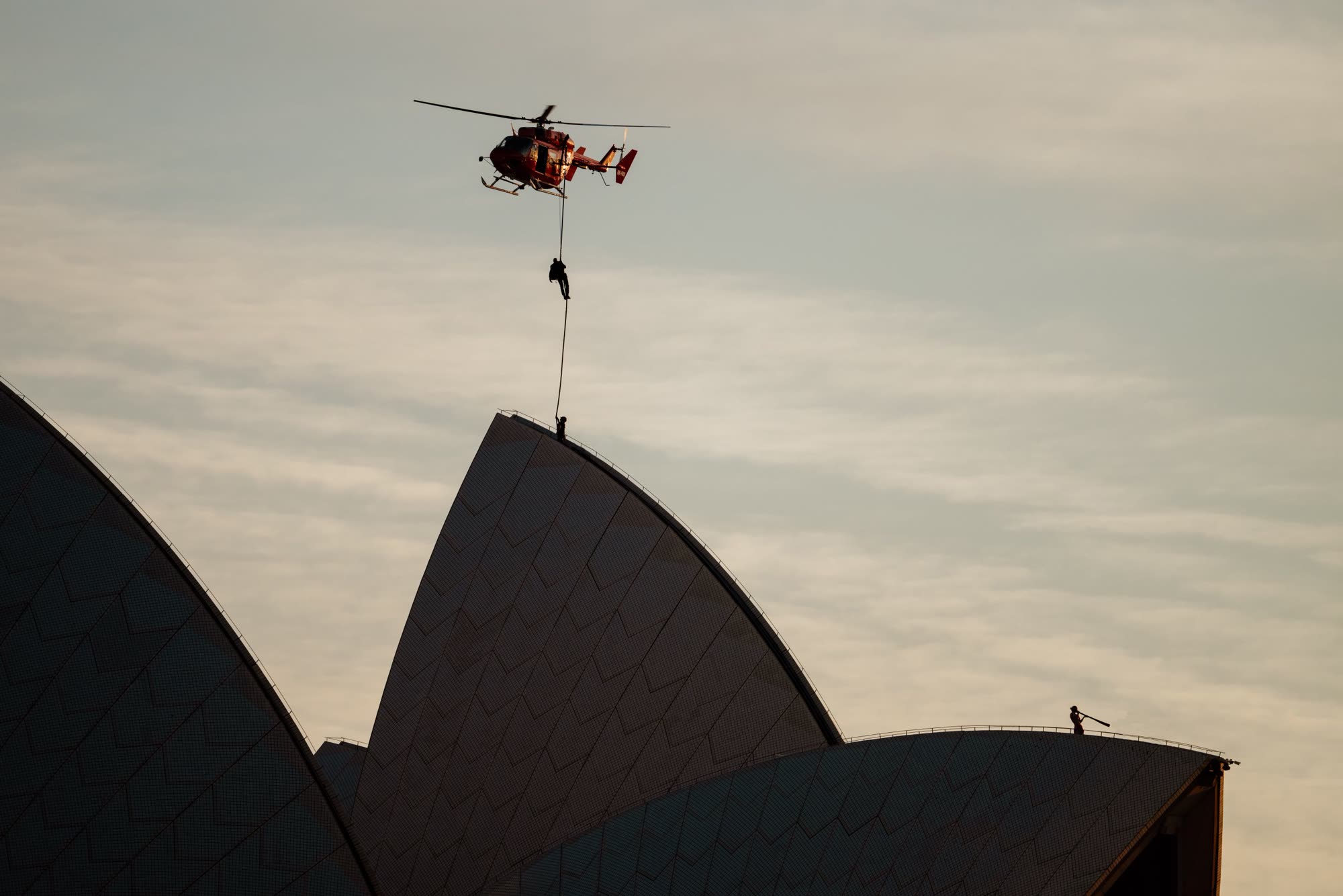 Stunt rappelling from a helicopter above Sydney Opera House at sunrise